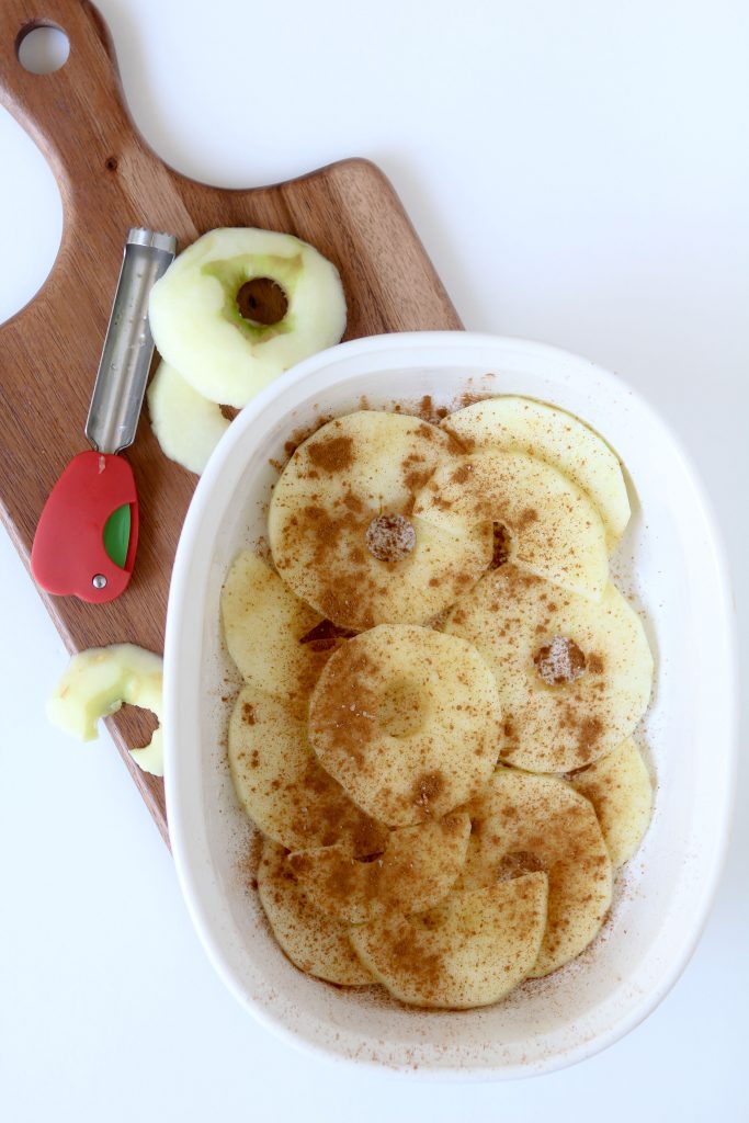 cinnamon dusted thinly sliced apples in a casserole dish