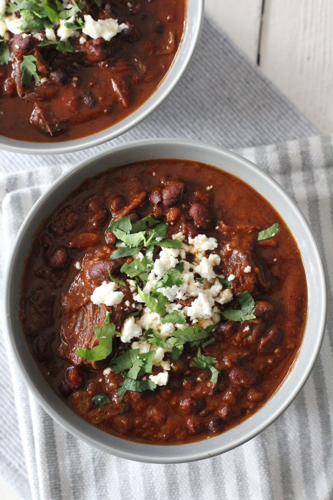 overhead shot of a bowl of short rib chili topped with crumbled cheese