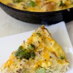 side view of a slice of healthy broccoli cheddar and chicken frittata on a white plate