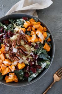 partial view of a quinoa bowl with kale, roasted sweet potatoes and dairy-free tahini dressing