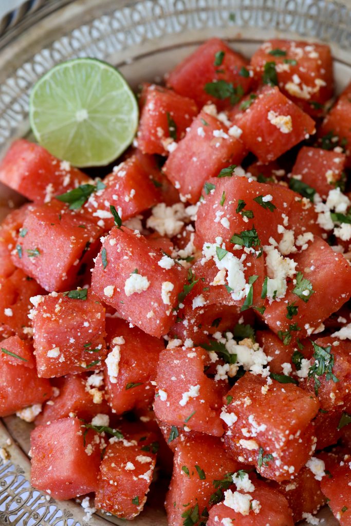 close-up of watermelon salad topped with queso fresco and chopped mint leaves 