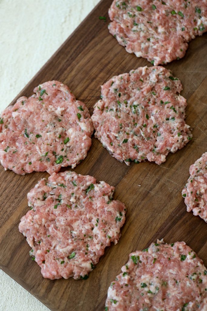 unbreaded flattened pork schnitzel made with ground pork placed on a wooden board 