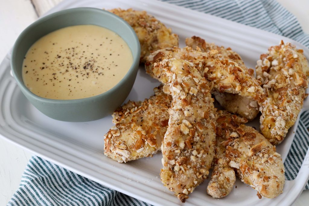 a serving of healthy gluten-free baked chicken tenders crusted with crushed pretzels served with honey mustard dip