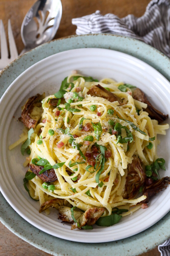 a bowl of carbonara pasta with artichokes